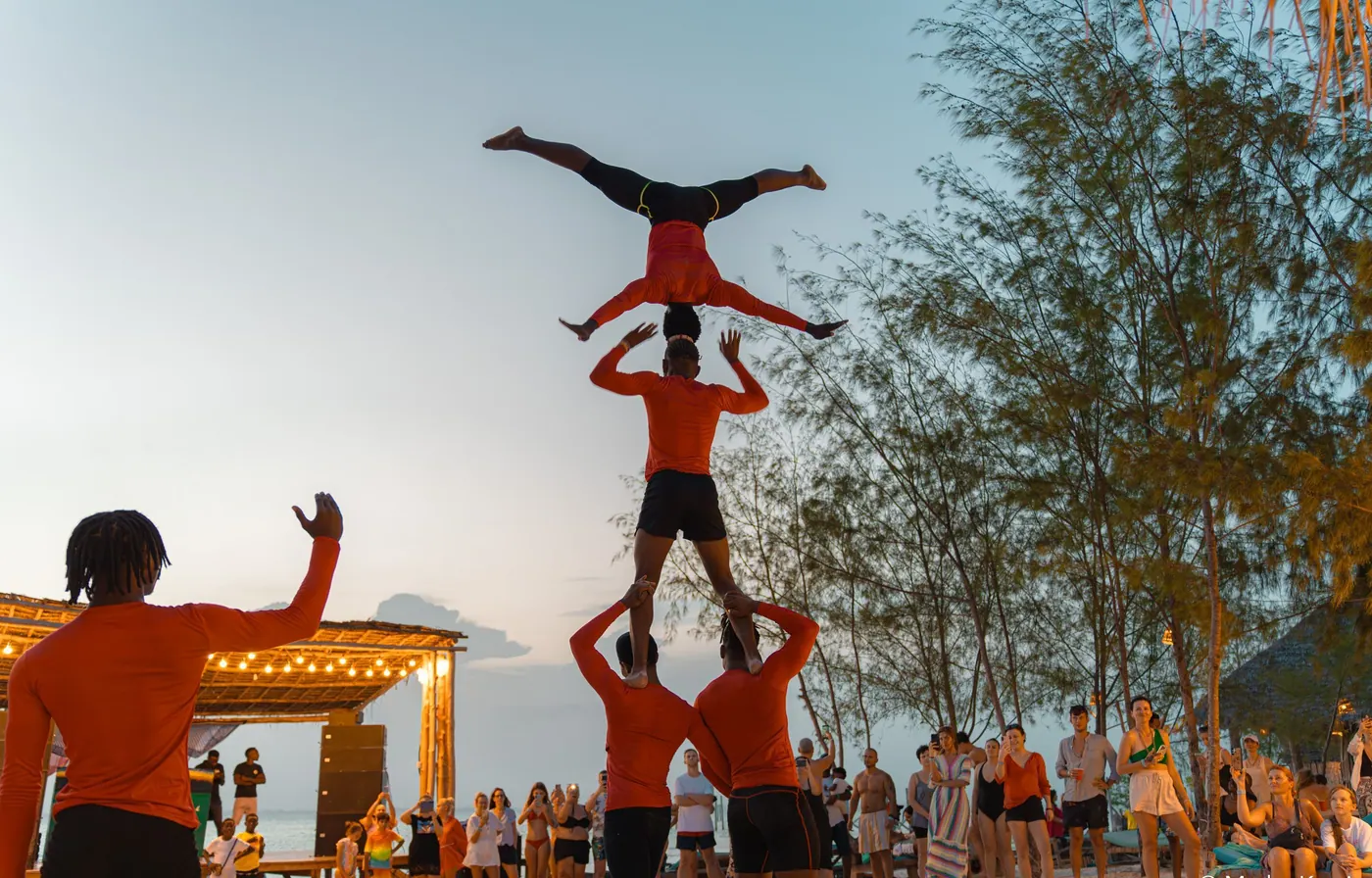 Acrobats forming a human tower on the beach at sunset, Kae Funk