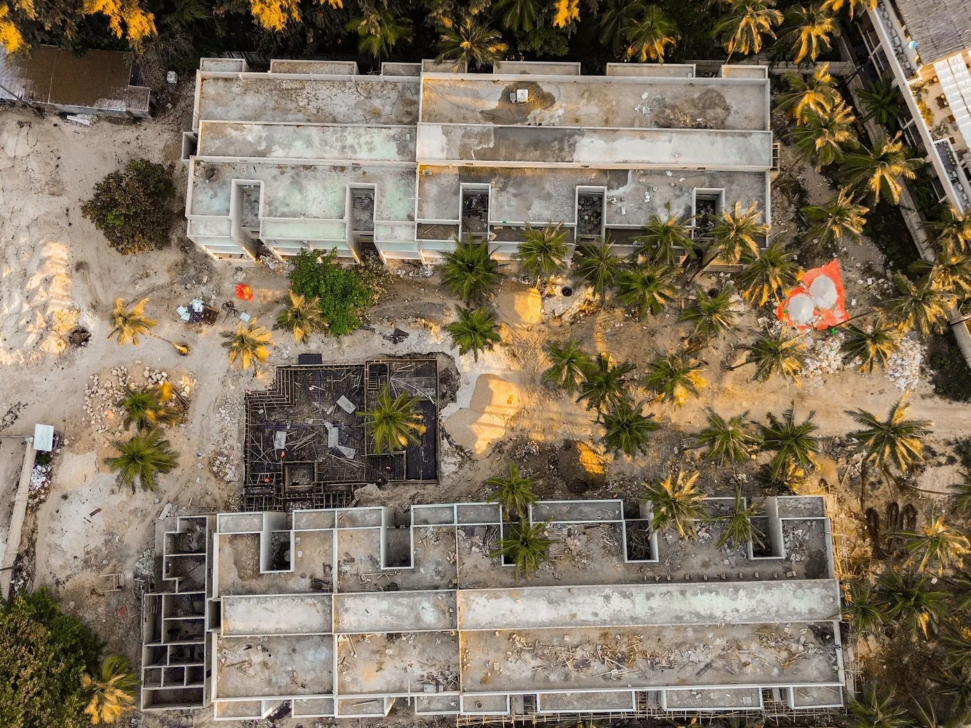 Two buildings under construction seen straight down from the drone, palms between them