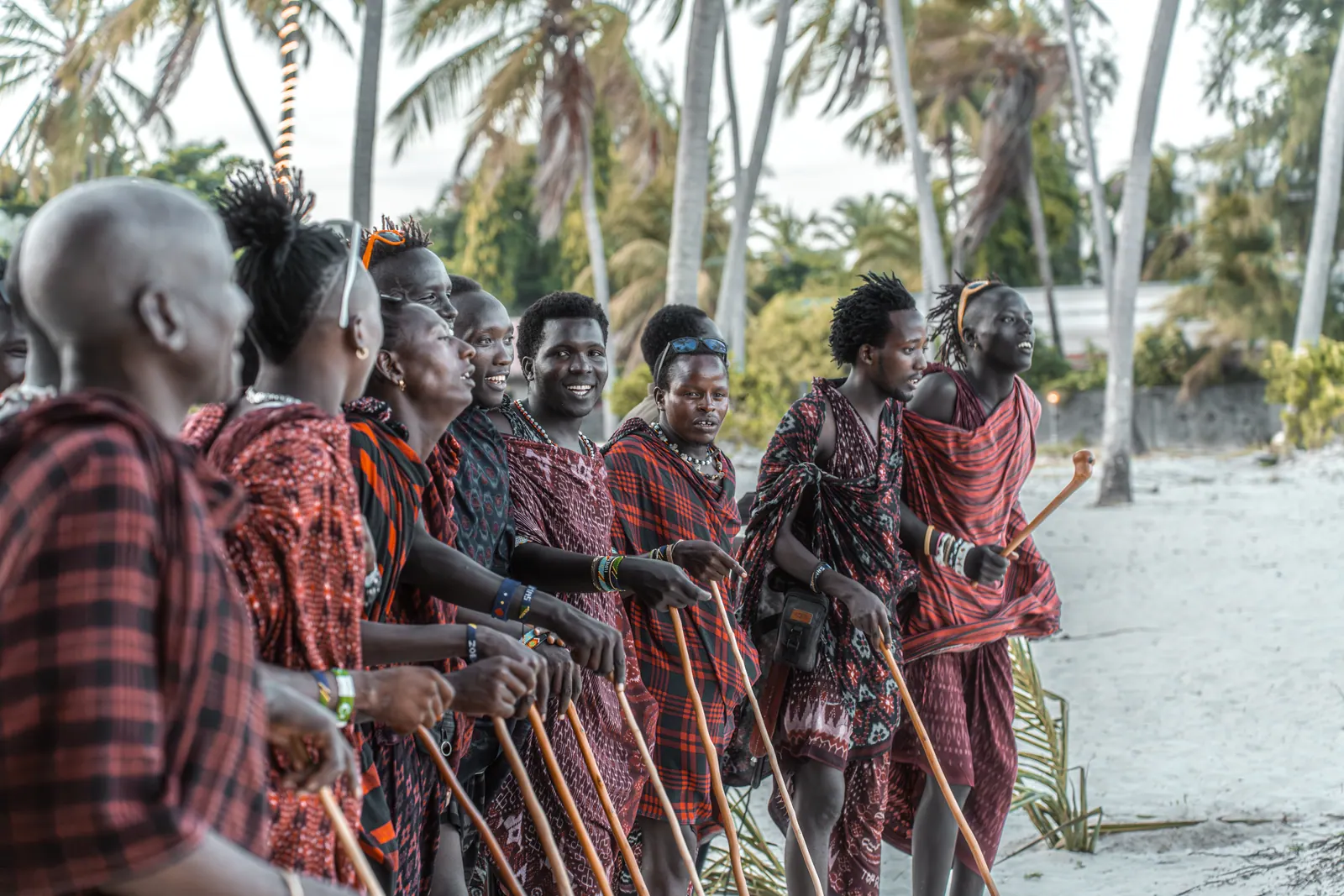 Maasai warriors in red and black lined up on the beach at the wedding