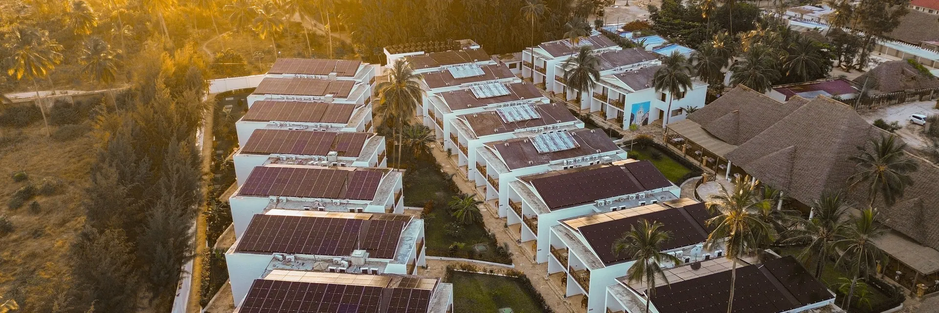 Resort villas with solar roofs at golden hour, seen from the drone